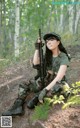 A woman in camouflage holding a rifle in the woods.