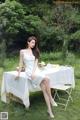 A woman in a white dress sitting at a table.