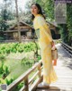 A woman in a yellow kimono standing on a wooden bridge.