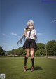 A girl in a school uniform standing on a grassy field.