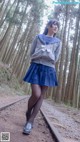 A woman in a school uniform standing on a train track.