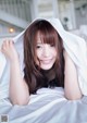 A woman laying on a bed under a white sheet.