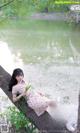 A woman sitting on a tree branch by the water.