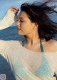 A woman standing on the beach with her hair blowing in the wind.