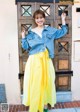 A woman standing in front of a wooden door wearing a yellow skirt.