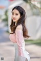 A woman in a pink and white dress posing for a picture.